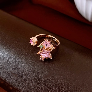 Detail of gold-plated star ring with pink crystals on dark brown leather texture