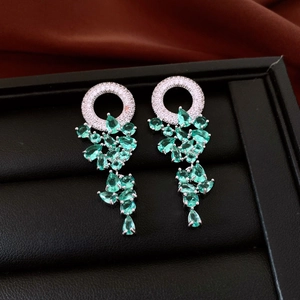 Macro detail of silver tassel earrings with green teardrop gemstones and zircon stones