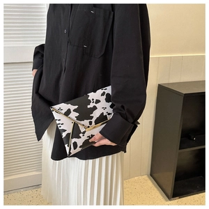 Detail of cow print envelope clutch bag with signature golden V-shaped metal trim