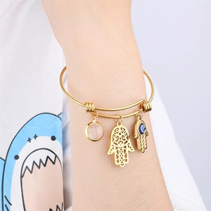 Gold stainless steel bangle featuring Hamsa, Evil Eye and zircon pendants on female wrist