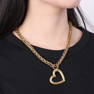 Close-up of a gold heart pendant necklace with a thick chain on a model's neck