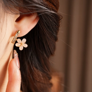 Macro view of floral drop earring with golden base, zircon, and pink resin petals