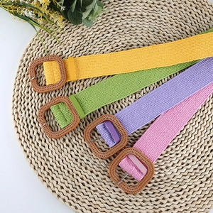 Detail of colorful elastic straw belts with textured square resin buckles on woven mat