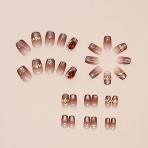 Macro shot of brown cat-eye gradient press-on nails with red gems and rhinestone details