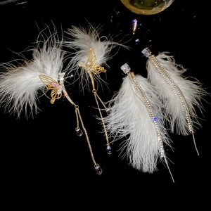 Detail of luxury long tassel feather earrings with crystals and butterfly pendants