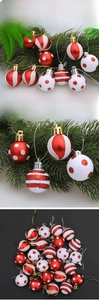 Detail of red and white Christmas baubles with stripes and dots hanging on pine branches
