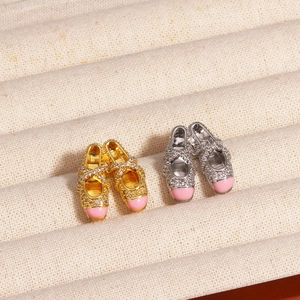 Detailed view of ballet slipper pendants in gold and silver with pink tips and crystals