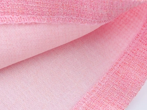 Makroaufnahme der rosa Tweed-Stoffstruktur und hochwertiger Kantenverarbeitung am Saum