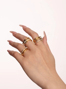 Detail of stacked gold and silver rings with zircons on model finger in light tone