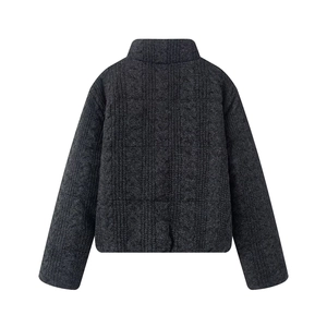 Close-up of dark grey chunky cable knit texture on back of warm padded jacket