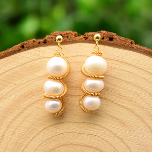 Handmade freshwater pearl drop earrings with gold wire on natural wood background