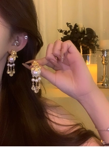 Détail de boucles d'oreilles vintage avec perles, monture dorée et pampilles élégantes