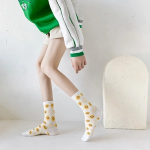 Detail of white cotton mid-calf socks featuring yellow smiley faces and SMILE lettering