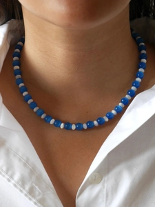 Detail of glacier blue cat eye beaded necklace with white spacers on a model collar