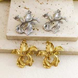 Minimalist 18k gold and silver stainless steel flower stud earrings set on travertine