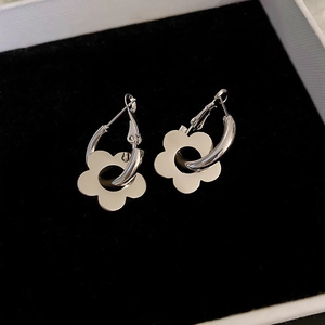 Macro view of silver flower geometric hoop earrings on black velvet padding