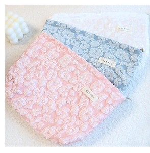 Detailed shot of textured cloud pattern makeup bags in pink, blue, and white colors