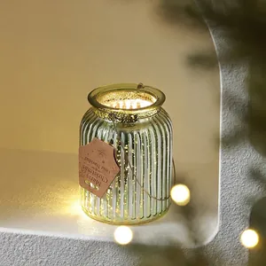Green ribbed glass Christmas candle lantern with warm lighting and a gold rim handle
