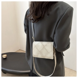 Detail of quilted beige crossbody bag with adjustable shoulder strap and gold hardware