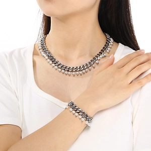 Close-up of silver Cuban link necklace and bracelet set with delicate pearl pendants