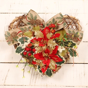 Christmas heart-shaped wreath with red silk flowers and pinecone ribbons on wood floor