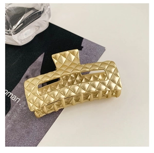 Detail shot of a luxury gold square hair claw clip with classic quilted diamond texture