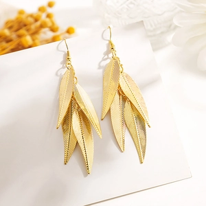 Gros plan de boucles d'oreilles en feuilles de métal dorées creuses avec fini brossé