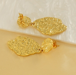 Macro shot of irregular gold leaf earrings with hammered texture and vintage metal finish