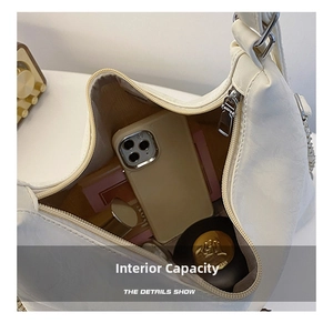 Detail shot of the spacious cream shoulder bag interior holding a phone and cosmetics