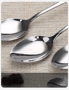 Polished stainless steel spoons with long handles in a set, macro view of metallic texture