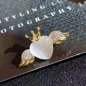 Macro detail of a golden crown heart brooch with sparkling wings on a stylish backdrop