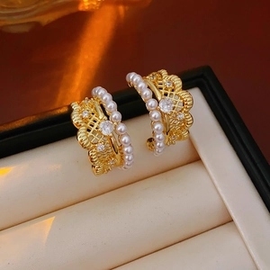 Close-up of vintage gold lace pearl earrings with central cubic zirconia and halo accents