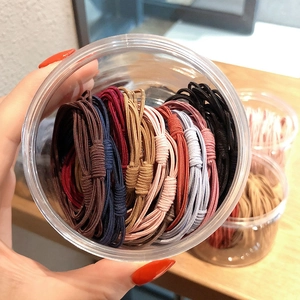 Close-up of colorful elastic hair ties neatly packed in a clear round plastic jar container