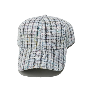 Detail of tweed baseball cap showing blue plaid texture and colorful sequins