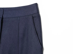 Vue détaillée du pantalon bleu marine montrant la texture sergé et les plis à la taille