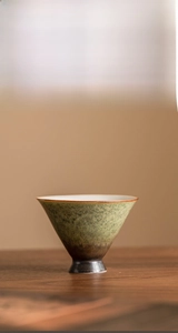 Detailed view of ceramic tea cup with green star kiln glaze and white inner surface