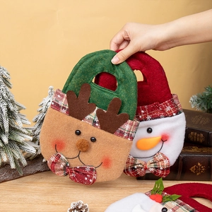 Christmas felt gift bags with reindeer and snowman designs on a festive wooden surface
