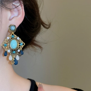 Detail view of vintage bronze diamond earrings with blue resin stones and pearl accents
