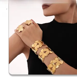 Macro detail of 18k gold butterfly rings and wide bangles with brushed metal texture