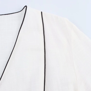 Detail of white top showing black contrast piping and textured cotton-linen fabric weave