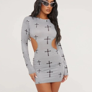 Détail d'une mini robe blanche avec motifs de croix noirs et découpes à la taille