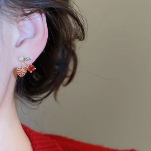 Close-up of heart-shaped cherry earrings with red cubic zirconia and green leaves