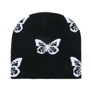 Dettaglio di un berretto in maglia nera con motivi di farfalle bianche jacquard