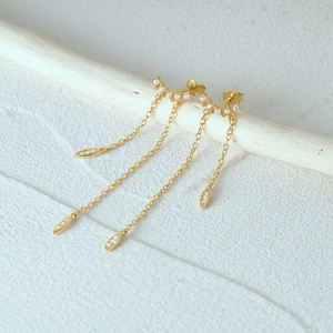 Macro shot of 925 silver gold tassel earrings with leaf charms and sparkling zircon