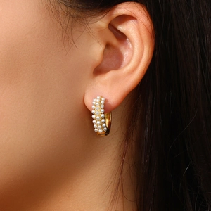 Close-up of 18K gold plated earring featuring elegant white pearls on the model