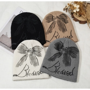 Detailed flat lay of knit beanies in four colors with bow and Blessed lettering