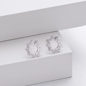 Minimalist S925 sterling silver sun stud earrings displayed on white geometric stands