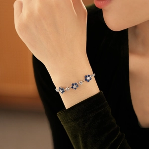 Detailed view of flower bracelet with blue and white zircons on a model's wrist