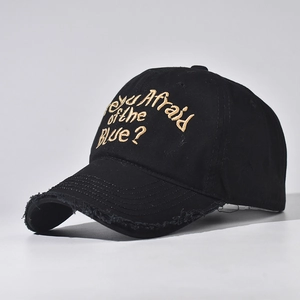 Close-up of golden embroidery and distressed brim details on a black cotton baseball cap