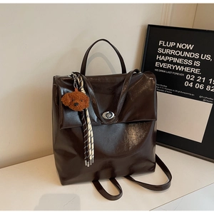 Detail of dark brown leather backpack with silver turn-lock and cute puppy pendant